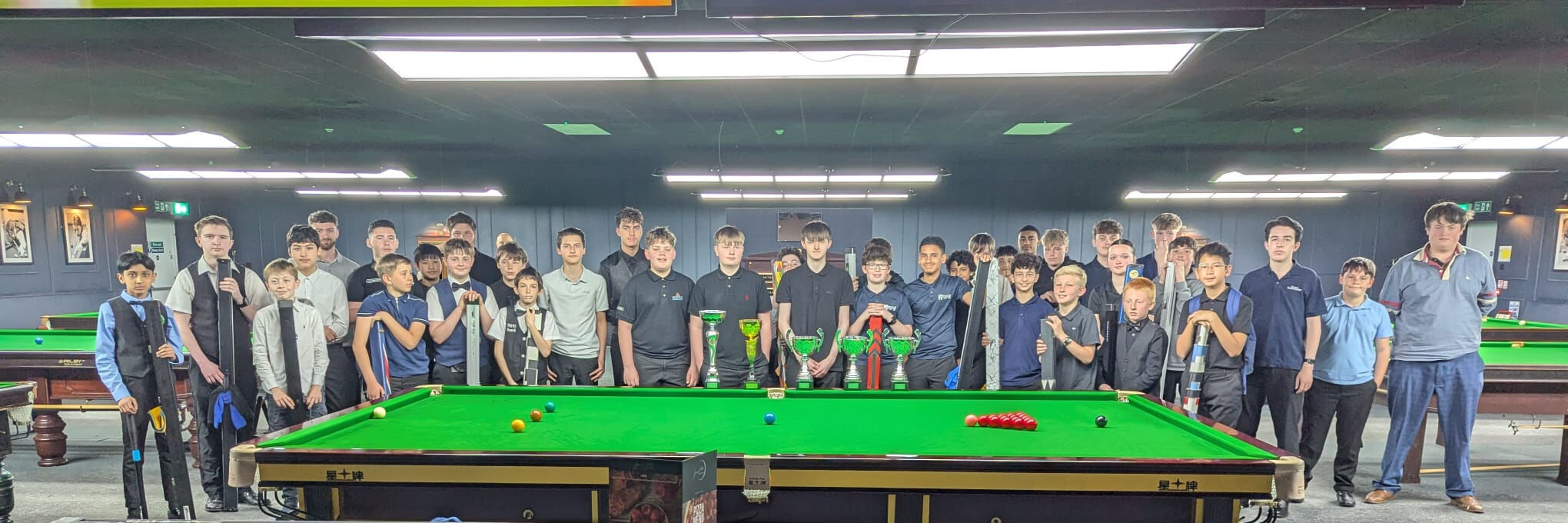 Young people standing behind a snooker table