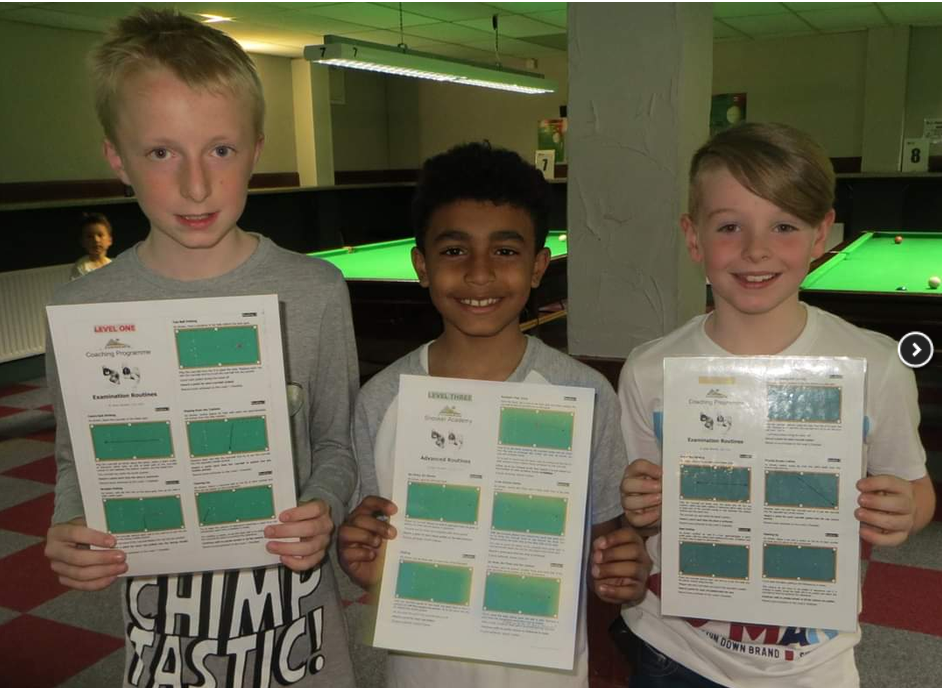 Three youths smiling and holding leaflets